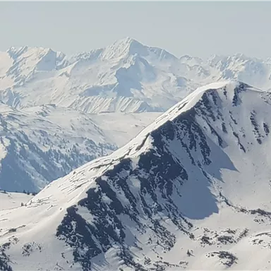 Eine atemberaubende Berglandschaft mit schneebedeckten Gipfeln. Der Himmel ist klar und das Licht reflektiert auf den weißen Felsen.