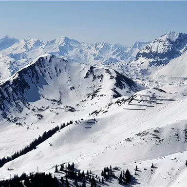 Eine malerische Winterlandschaft mit schneebedeckten Bergen. Der klare Himmel bietet eine atemberaubende Aussicht auf die umliegenden Gipfel.