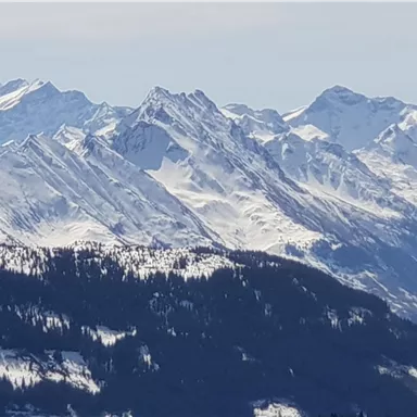 Eine beeindruckende Gebirgslandschaft mit schneebedeckten Spitzen. Der Himmel ist klar und die Berge wirken majestätisch.