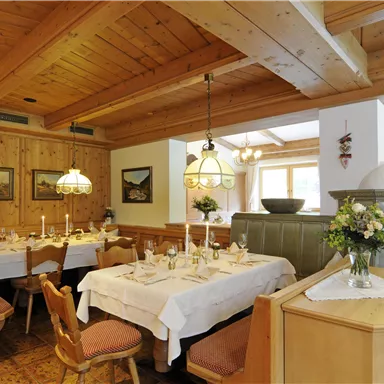 A cozy restaurant with wood paneling and elegant table settings. Soft light from chandeliers creates an inviting atmosphere.