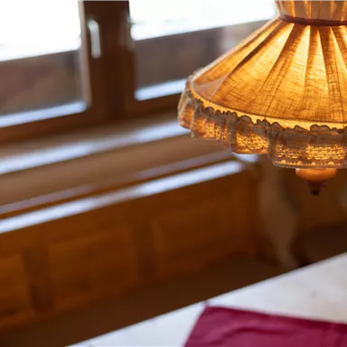 A cozy room with a warm lamp and a window in the background. On the table lies a red cloth.