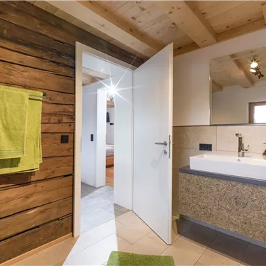 A modern bathroom with wood paneling and a stylish sink.  
Bright green towels hang on the wall.