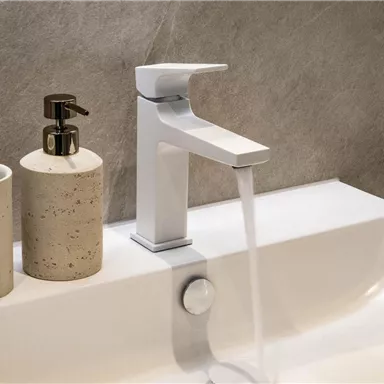 Ein modernes Waschbecken mit einem eleganten Wasserhahn. Neben dem Waschbecken stehen zwei dekorative Behälter.