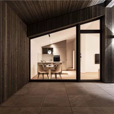 Ein modernes Wohnzimmer mit einem Esstisch und eleganten Stühlen ist durch große Fenster sichtbar. Die Wände sind aus Holz und sorgen für eine gemütliche Atmosphäre.
