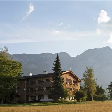 Ein schönes Gebäude in einer ländlichen Umgebung mit hohen Bergen im Hintergrund. Die Landschaft ist grün und weiträumig, ideal für Naturliebhaber.