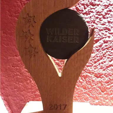 A wooden trophy with a stylized flame and a round medal in the center. The trophy bears the inscription "Landlord Award 2017" and the name "Waldhof".
