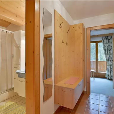 Ein heller Flur mit einem Badezimmer auf der linken Seite und einem großen Fenster auf der rechten Seite. Die Wände sind in sanften Farben gehalten und es gibt Holzdetails.