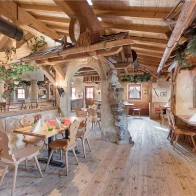 A cozy restaurant with wooden decor and a rustic atmosphere. The tables are lovingly set, and there is a fireplace in the corner.