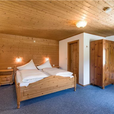 Ein schlichtes Schlafzimmer mit Holzdecke und Holzschlafzimmermöbeln. Das Zimmer bietet ein Doppelbett und einen Kleiderschrank in einem gemütlichen Ambiente.