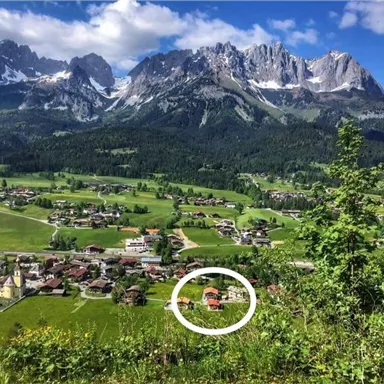 A picturesque landscape with mountains in the background and a small village in the foreground. The nature is green and lush, ideal for relaxation and hiking.