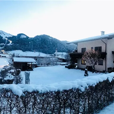 Ein schöner Wintertag mit schneebedeckten Häusern und Bergen im Hintergrund. Die Landschaft ist ruhig und idyllisch, mit einem weißen Schneeüberzug.
