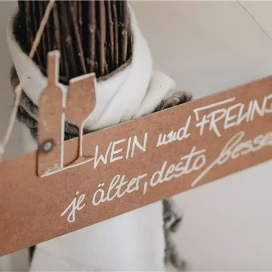 A decorative wooden sign with the inscription "WINE and FRIENDS, the older, the better." It conveys a stylish and inviting atmosphere.