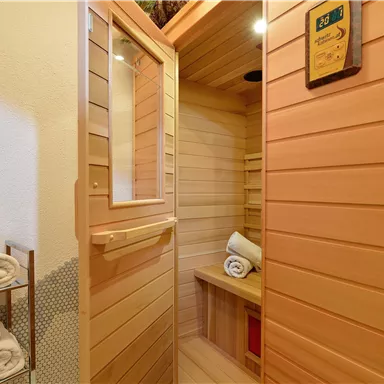 A cozy wooden sauna with towels and soft lighting. The room offers a relaxing atmosphere for unwinding.
