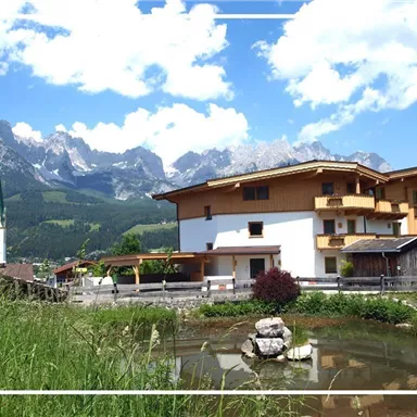 A picturesque village with traditional buildings and a majestic mountain landscape in the background. The sky is clear and blue, perfect for a holiday atmosphere.