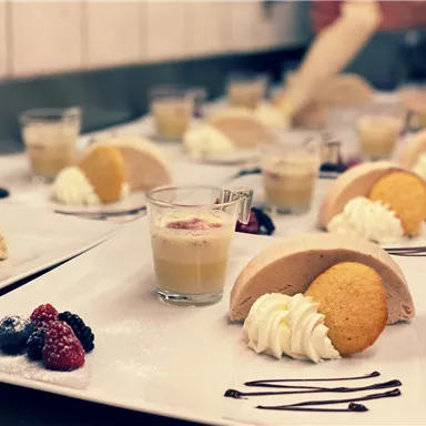 A beautifully arranged dessert plate with various delicacies. It contains cream, cookies, whipped cream, and fresh berries.