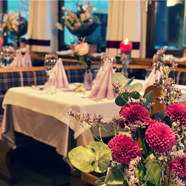 A beautifully decorated table in a restaurant with fresh flowers and candles. The plates and napkins are carefully arranged to create an inviting atmosphere.