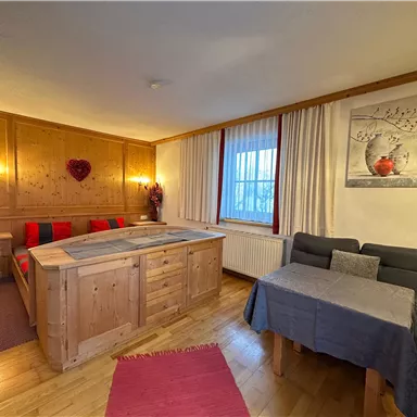 A cozy room with wooden furniture and a large window. There is a bed and a table with chairs.