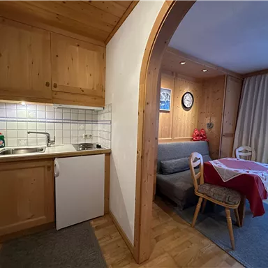 A cozy kitchen with wooden cabinets and a dining area. The room has a warm, inviting character.