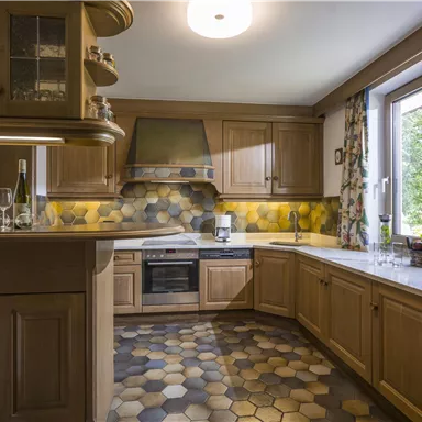 A modern kitchen with wooden cabinets and a light, attractive floor. The window offers a view outside and provides daylight.