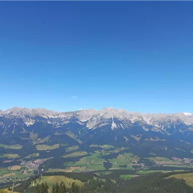 An impressive mountain landscape with majestic peaks and green valleys. The clear blue sky enhances the beauty of nature.