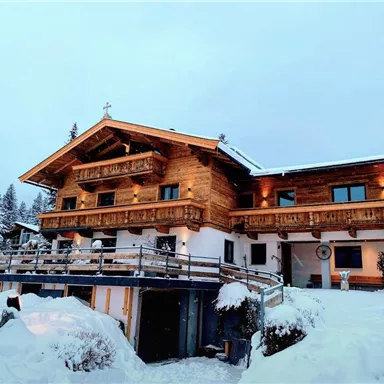Ein hübsches Holzhaus im Schnee, umgeben von Tannenbäumen. Die Fassade ist gemütlich und einladend.