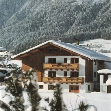 Ein charmantes Chalet im Schnee, umgeben von schneebedeckten Bergen. Die kalte Winterlandschaft vermittelt eine gemütliche Atmosphäre.