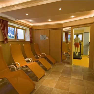 A relaxing wellness area with loungers and large windows. The room is bright and inviting, ideal for relaxation.
