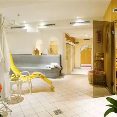 A relaxing wellness area with a sauna and cozy seating areas. The decor is bright and friendly, surrounded by plants and shades of orange.