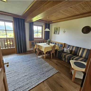 A cozy living space with wooden paneling and a large window. A dining table and seating area invite you to linger.