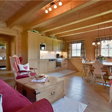 Eine gemütliche Holzwohnung mit modernen Möbeln und einem einladenden Essbereich. Große Fenster bieten viel Tageslicht und Atmosphäre.
