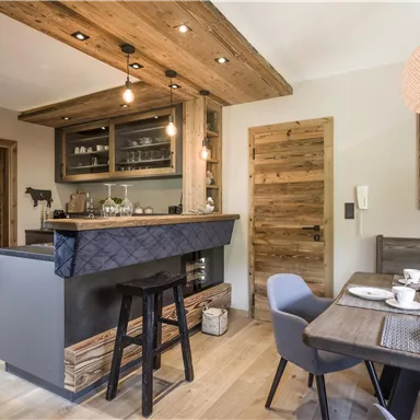 A modern kitchen with wooden elements and a minimalist counter area. The dining area is elegantly set and creates a cozy atmosphere.