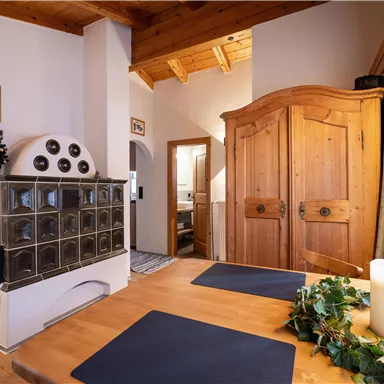 An inviting living space with a wood stove and a large wooden cupboard. The table is set and there is a decorative candle.
