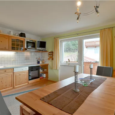 A cozy kitchen with wooden cabinets and a dining area. The window offers a view of the outdoors and lets in plenty of light.