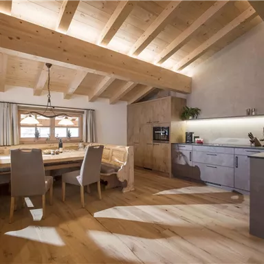 Ein modernes und gemütliches Esszimmer mit Holzmöbeln. Große Fenster lassen viel Licht hereinfliessen und schaffen eine einladende Atmosphäre.