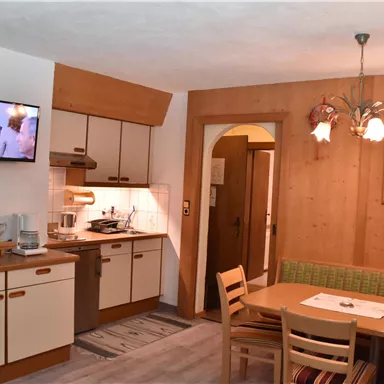 A cozy kitchen with a dining area in a wood look. The room is bright and inviting, with modern appliances and a TV corner.