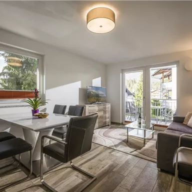 A modern living room with a cozy couch and a dining area.
Large windows provide plenty of daylight and a view of the outdoors.