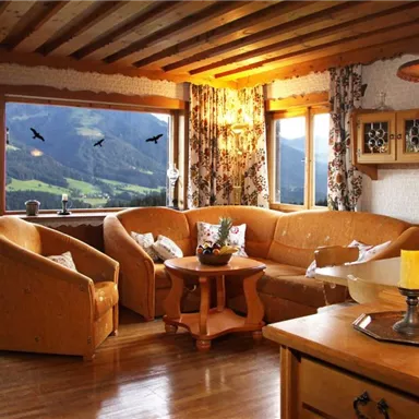 A cozy living room with a large sofa and two armchairs. Through the windows, a view of the mountains and a harmonious interior design.