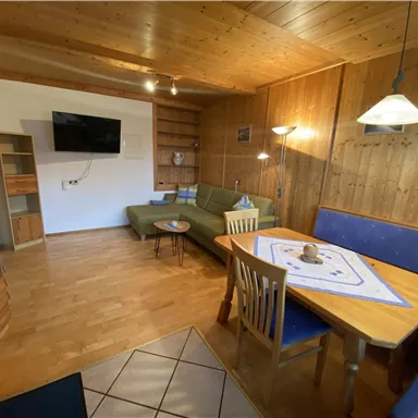 A cozy living room with wooden paneling and a modern seating area. The dining area is inviting and well-lit.