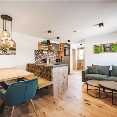 Ein modernes Wohnzimmer mit einer gemütlichen Couch und einem Essbereich. Der Raum ist hell und einladend mit Holzfußboden und stilvollen Lichtern.
