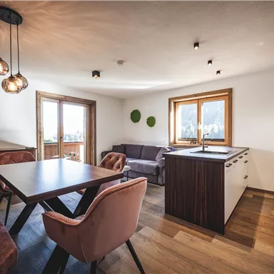 Ein modernes Wohnzimmer mit gemütlichen Möbeln und großen Fenstern. Die Einrichtung kombiniert Holz- und Metallmaterialien für einen stilvollen Look.