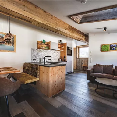 Eine moderne Küche mit einem Essbereich und einem gemütlichen Wohnzimmer. Helles Holz und eine einladende Atmosphäre schaffen ein angenehmes Wohngefühl.
