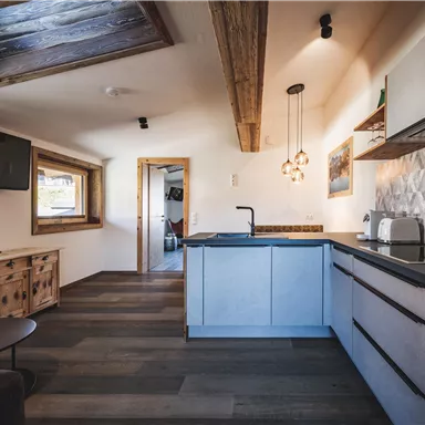 Eine moderne Küche mit Holzdetails und gemütlicher Einrichtung. Sie verfügt über einen Essbereich und viel natürlichen Licht.