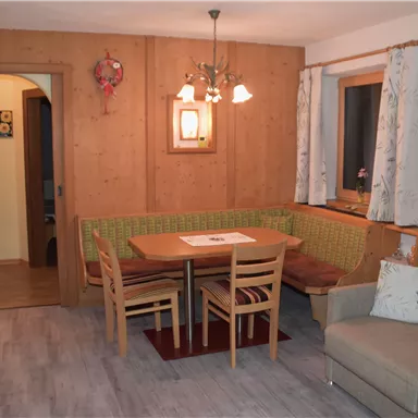 A cozy living space with wooden paneling, a dining table, and a corner bench. The lighting creates a relaxed atmosphere.