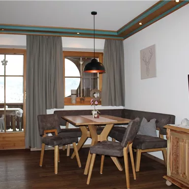 A cozy dining area with a wooden table and chairs. Large windows provide a view outside and let in plenty of light.