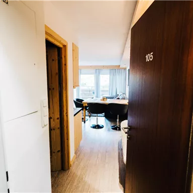 A view of the hallway in front of room 105. Through the door, you can see a small table and chairs in the background.
