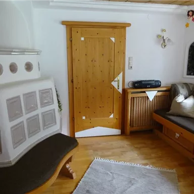 A cozy living space with wood decor and an adjacent door. Cushions are on the bench and a rug is on the floor.