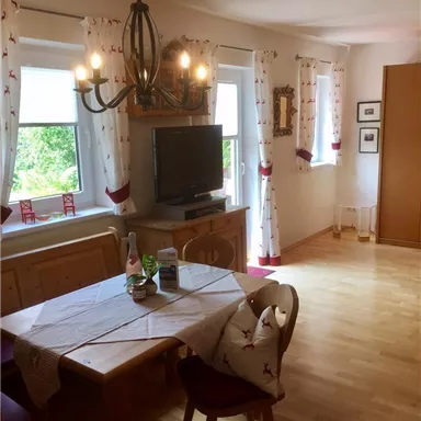 Ein gemütlicher Essbereich mit einem Holz-Esstisch und modernen Stühlen. Großzügige Fenster lassen viel Tageslicht hereinfließen.