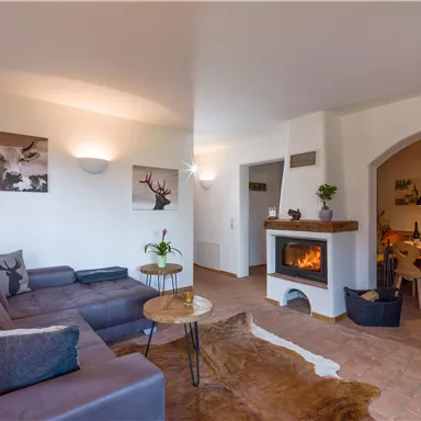 Ein gemütliches Wohnzimmer mit einer modernen Couch und einem Kamin. Die Wände sind hell und mit dekorativen Bildern geschmückt.