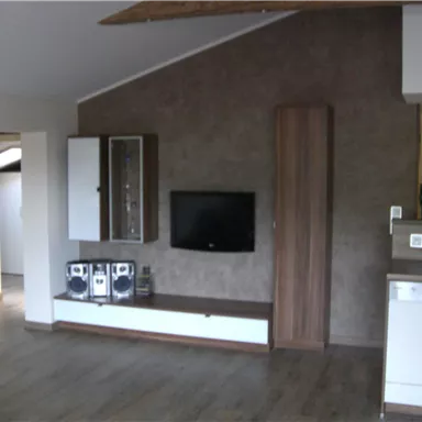 A modern living room with a TV on the wall and an elegant cabinet. The floor is made of wood and the walls are in neutral colors.