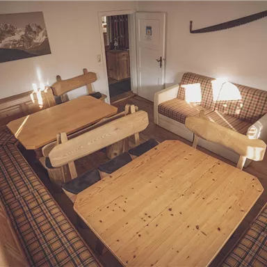 Ein gemütlicher Raum mit Holzstühlen und -tischen. Das Interieur hat eine warme Atmosphäre mit einer schönen Aussicht auf die Berge.